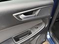 Close-up of the door panel of a 2017 Ford Edge featuring a textured surface a silver door handle and controls for window operation