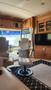 Interior of a 2007 Winnebago Adventure featuring a motorized recliner and a swivel chair next to a television and wooden cabinetry