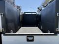 A 2023 Ford F-550 truck with an empty, flatbed cargo area featuring side storage compartments and a clean textured surface