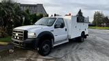 A white 2007 Ford F-550 with an extended cab and service body features utility boxes and multiple amber lights on top