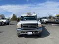 A 2003 Ford F-450 SD with a white exterior and a front grill visible is parked with a plow attached to its front end