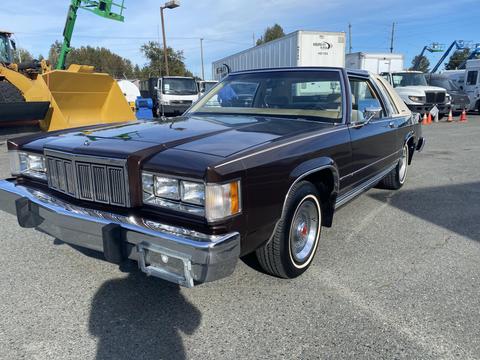 A 1982 Mercury Grand Marquis with a dark brown exterior and chrome accents parked on asphalt showcasing its classic design and detailing