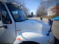 2011 International DuraStar 4300 truck with a white exterior and prominent side mirrors parked on a street