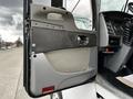 The interior door panel of a 2014 Kenworth T370 truck featuring a handle and various controls