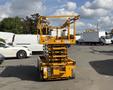 A yellow 2013 Haulotte Compact scissor lift with elevated platform and safety rails in the upright position