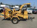 A yellow 2010 Vermeer Corporation BC1200XL wood chipper with a feed chute on the right side and a trailer hitch at the front