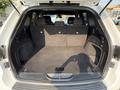 The trunk of a 2020 Jeep Grand Cherokee showing a spacious cargo area with a carpeted floor and upright rear seats folded down