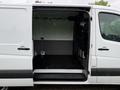 A 2016 Mercedes-Benz Sprinter van with the side door open showing a spacious cargo area featuring a metal partition and a flat floor