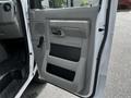 A close-up view of the inside door panel of a 2018 Ford Econoline showing the handle and storage compartment