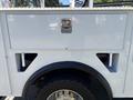 A white 2016 Ford F-550 with a shiny silver tool compartment and black tires visible on the side of the vehicle