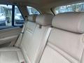 Interior view of a 2009 BMW X5 showcasing beige leather rear seats with headrests and a seatbelt visible in the middle