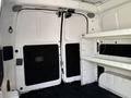 Interior view of a 2021 Nissan NV200 showcasing the rear doors and a white shelving unit on the right side of the cargo space