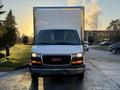 A white 2015 GMC Savana cargo van is facing forward with a gray box in the back and a clean windshield