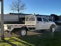 A white 2014 RAM 5500 pickup truck with a flatbed and built-in storage compartments on the sides