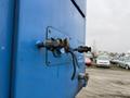 Close-up of a blue panel on a 2011 Freightliner Cascadia Nordic featuring a connector and valve assembly with hoses attached