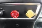 Close-up of control panel featuring a red air supply knob labeled Evacuate and a yellow oil level indicator both set in a black and silver dashboard