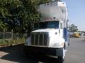 A white and blue 2008 Peterbilt PB340 truck with a raised cab and multiple orange lights on top