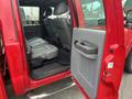 A red 2011 Ford F-250 SD with a focus on the open rear door revealing the backseat area and interior features