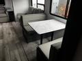 A cozy dining area with a marble-top table and light gray upholstered seating in a 2022 Aspen Trail travel trailer