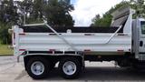 A white 2014 International 7500 dump truck with a raised bed and a black tarp covering the load area