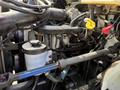 Engine components of a 2011 International 4300 with various hoses and connectors visible alongside a cylinder and reservoir
