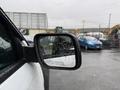 A 2019 Ford Explorer captured from the driver's side showing the side mirror with raindrops on its surface and a reflection of vehicles in the background