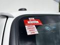 A 2018 Ford Econoline with a red certificate of approval sticker on the window displaying the years 2026 and months January February March April