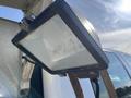 A close-up of a square floodlight mounted on a metal bracket with a clear lens and black casing