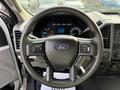 A steering wheel of a 2020 Ford F-550 featuring buttons for audio and cruise control with the Ford logo in the center