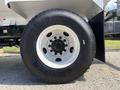 A close-up view of a 2016 Ford F-750 tire showcasing a black rubber tread with a white rim and multiple lug nut holes in the center