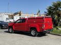 A red 2018 GMC Canyon pickup truck with an aftermarket bed cover parked on a paved surface