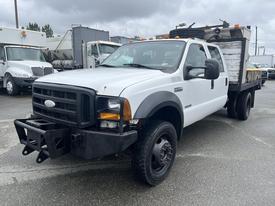 A 2007 Ford F-450 SD truck with a white exterior and a flatbed, featuring black wheel rims and front bumper details