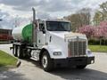 A white 1996 Kenworth T800 truck with a green tank trailer and chrome details is parked with its front visible