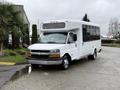 A white 2013 Chevrolet Express shuttle bus with large windows and a high roof is parked with its front facing the viewer