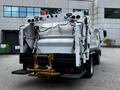 A 2014 Hino 195 garbage truck with a rear-loading design featuring a hydraulic compactor and visible wiring on the back panel
