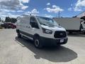 A white 2019 Ford Transit van with a black front grille and side windows parked on a concrete surface