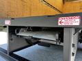 A 2020 Hino 155 truck showing the loading ramp mechanism with warning labels about hooking the ramp into the slot before use