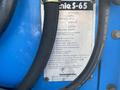 A blue and silver plate on a Genie S-65 4X4 aerial lift providing details like model number weight capacity and specifications
