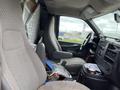 Interior of a 2014 GMC Savana with two gray cloth seats and a dashboard filled with various items and clutter