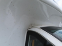 A close-up view of a 2020 Chevrolet Express showing the transition between the vehicle's roof and side panel with slight wear and a visible seam
