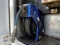 A blue hose reel with a coiled hose attached positioned inside a storage compartment of a vehicle