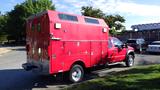 A red 2010 Ford F-550 with a customized utility bed and multiple storage compartments on the sides