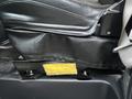 A close-up view of the seat mechanism in a 2017 Chevrolet Express showing a black leather seat with a yellow label on the side