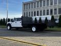 A 2018 Ford F-450 Super Duty truck with a flatbed and black storage boxes on the sides parked on the side of the road