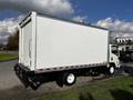 A white 2016 Isuzu NPR box truck with a smooth surface and no visible markings on the cargo area is parked with its rear doors closed