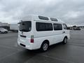 A white 2002 Nissan Van with a high roof and side windows parked in a lot