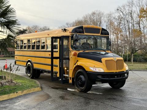 A yellow 2013 International 4300 school bus with an open door parked on a road