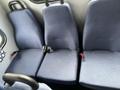 A row of three blue fabric seats inside a 2012 Chevrolet Express van with seatbelt latches visible on two seats