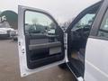 A white 2013 Ford F-150 with an open driver's door revealing the interior dashboard and seating area