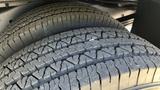 Close-up of two worn tires with distinct tread patterns mounted on a 2011 Chevrolet Express